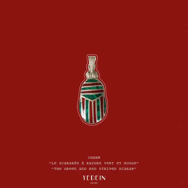 Le charm Le Scarabée à rayures vert et rouge présenté sur fond rouge est épuisé