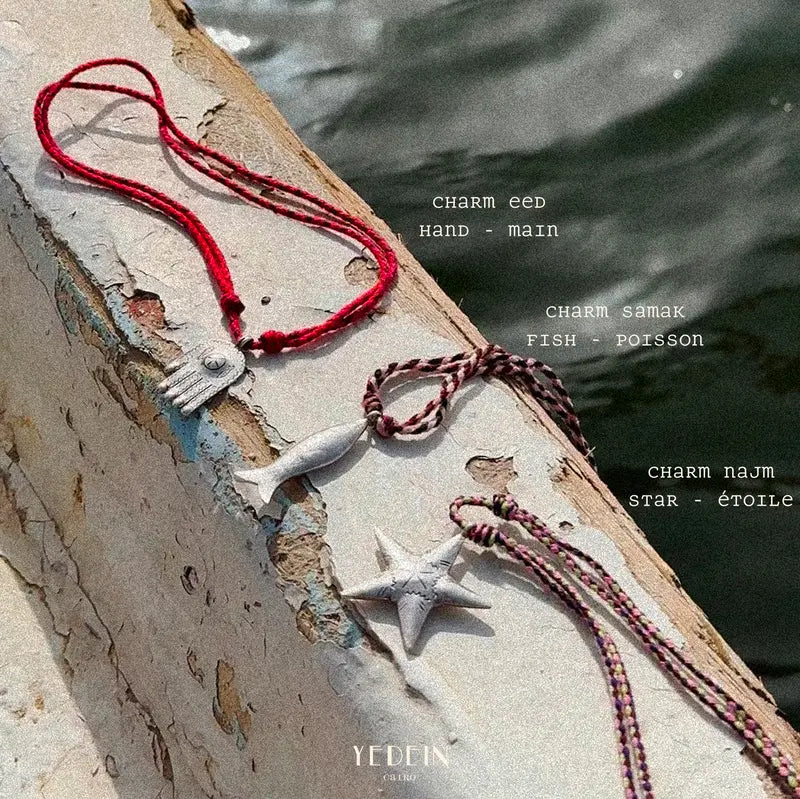 Charms individuels en argent Samak, Eed et Najm présentés sur le rebord d'un bateau