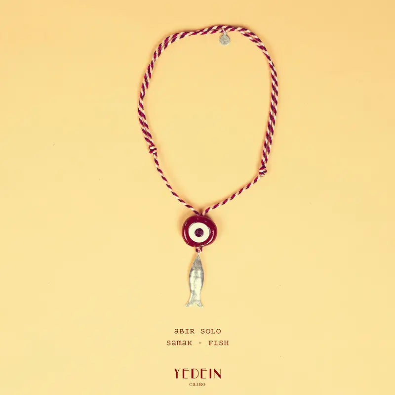 Collier Abir Solo avec un œil rouge rouille et un charm Samak sur fond beige