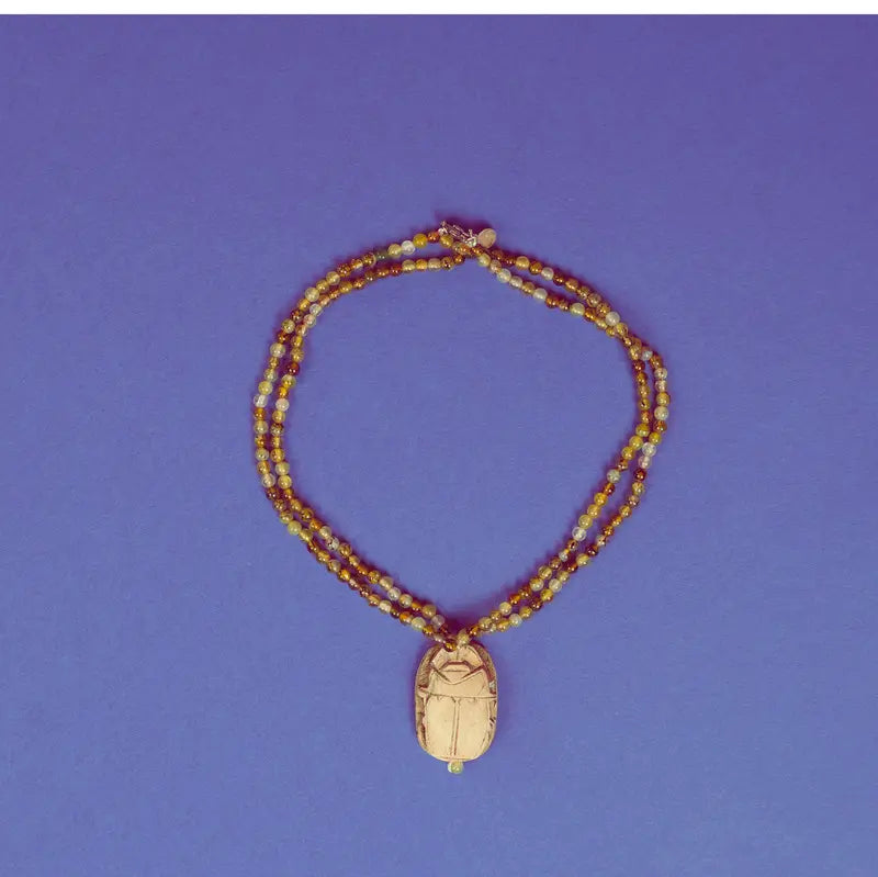 Collier scarabée en stéatite et perles d'agate verte sur fond bleu
