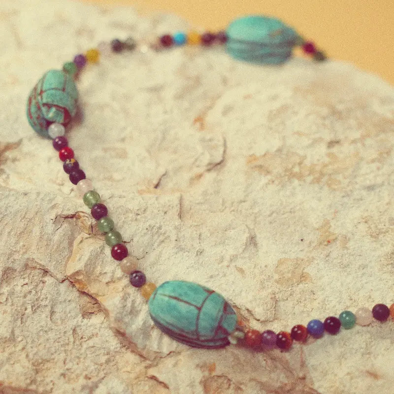 Collier Hayat avec scarabées vert d’eau présenté sur une pierre