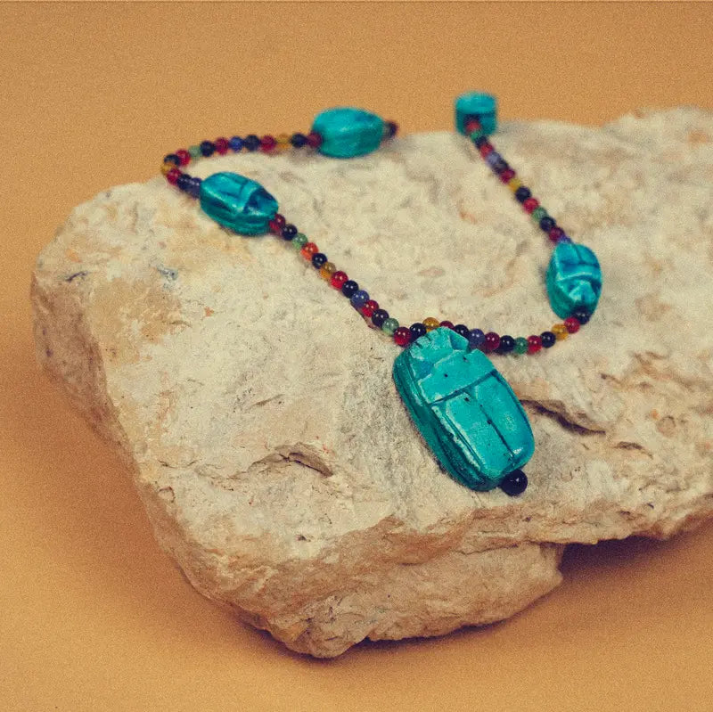Collier Haz avec scarabées en stéatite émaillée présenté sur une pierre
