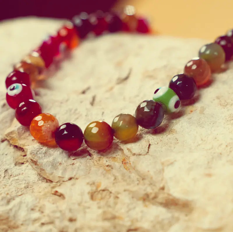 Collier Okht aux tons rouge posé sur une pierre