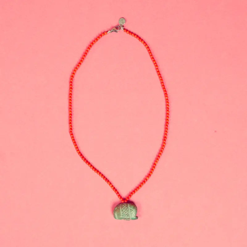 Collier Qowa artisanal posé sur fond rose