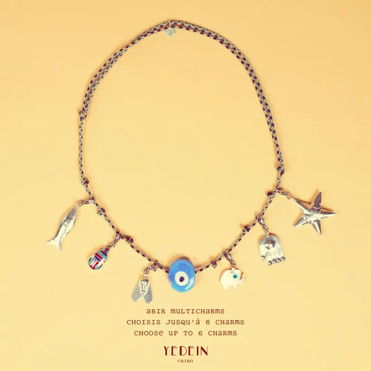 Collier Abir Multicharms avec six charms sur fond beige