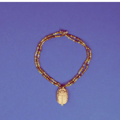 Collier scarabée en stéatite et perles d'agate verte sur fond bleu