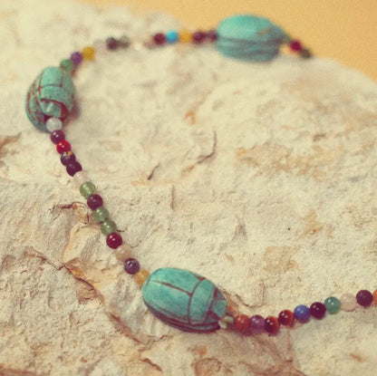 Collier Hayat avec scarabées vert d’eau présenté sur une pierre