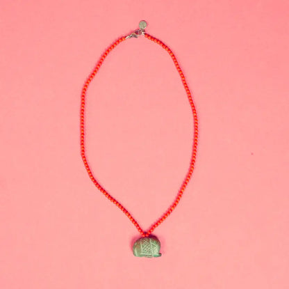 Collier Qowa artisanal posé sur fond rose