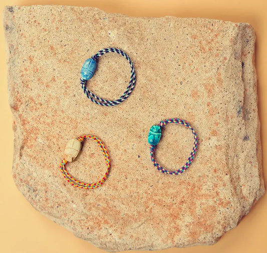 Présentation de trois bracelets scarabée posés sur une pierre et vue d'en haut