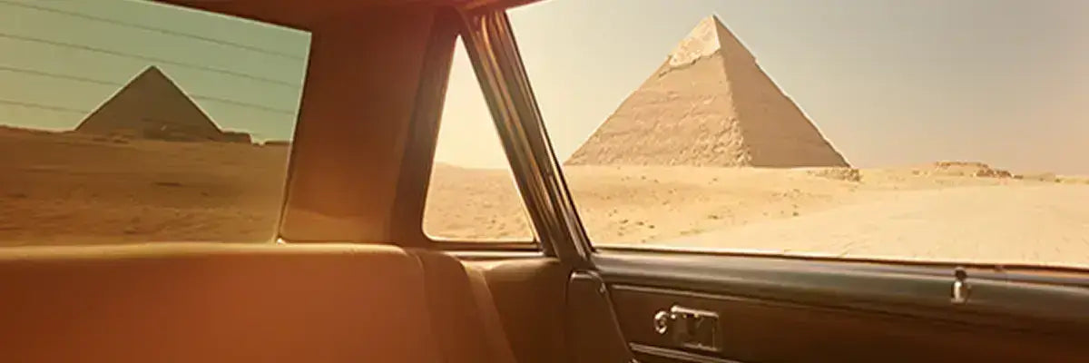Vue sur les pyramides de l'intérieur d'un taxi égyptien pour représenter la page notre histoire